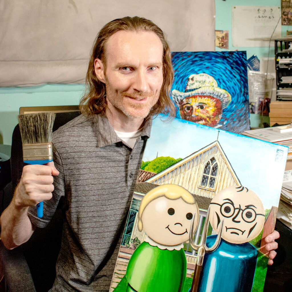 Artist Chris Hilbig holding his painting, "Little Gothic" while holding a brush.